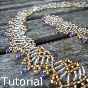 Puede incluir: Un collar de cuentas doradas y plateadas con un patrón geométrico y cuentas iridiscentes moradas. El collar está sobre una superficie de madera. Tutorial.
