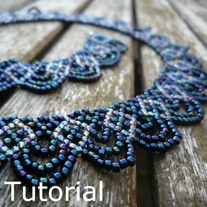 May include: A close-up of a dark blue beaded necklace with a scalloped design. The necklace is made of small, iridescent beads that create a shimmering effect. The necklace is lying on a wooden surface.