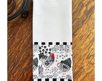 Pode incluir: Toalha de cozinha branca com uma borda preta e branca com um design de galo e galinha. A borda tem um padrão xadrez preto e branco.
