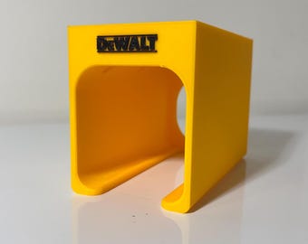May include: A yellow plastic tool holder with the word "DEWALT" printed on the front. The holder has a slot for holding a tool.