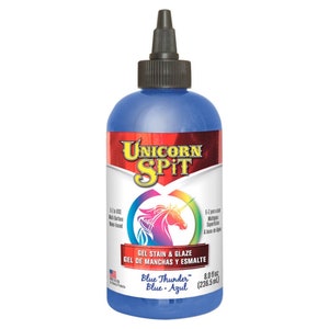 May include: A blue bottle of Unicorn Spit gel stain and glaze. The label features a unicorn graphic with rainbow colours and the text "Blue Thunder". The bottle contains 236.5 ml of product.