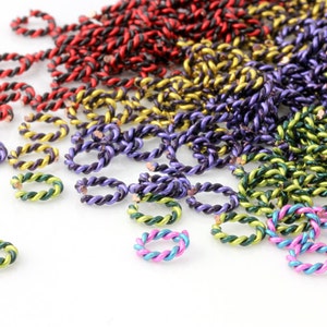 May include: A large pile of colorful twisted wire rings. The rings are in shades of red, orange, yellow, green, purple, blue, and pink.