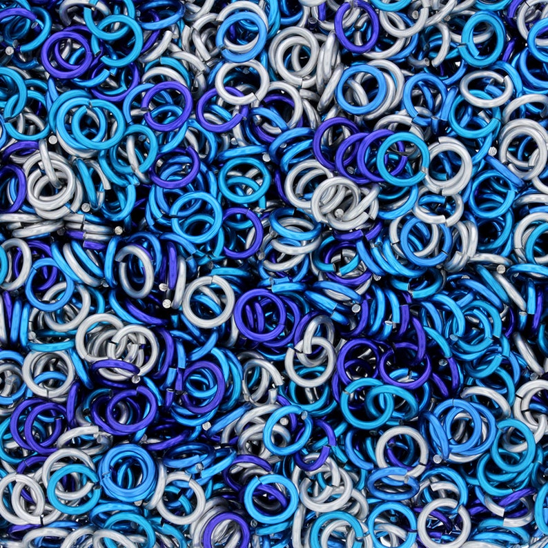 Puede incluir: Primer plano de un mont&oacute;n de anillos de salto de metal plateado y azul. Los anillos est&aacute;n entrelazados y crean un fondo texturizado y met&aacute;lico.