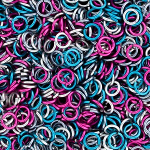 Puede incluir: Primer plano de un mont&oacute;n de peque&ntilde;os anillos met&aacute;licos en plata, azul turquesa y magenta.