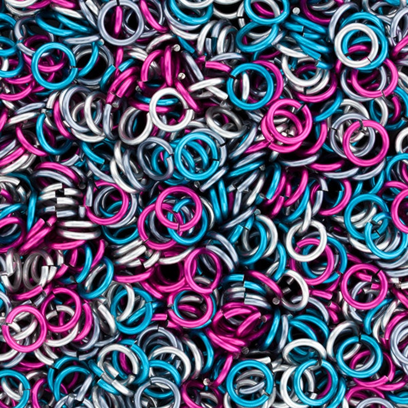 Puede incluir: Primer plano de un mont&oacute;n de peque&ntilde;os anillos met&aacute;licos en plata, azul turquesa y magenta.