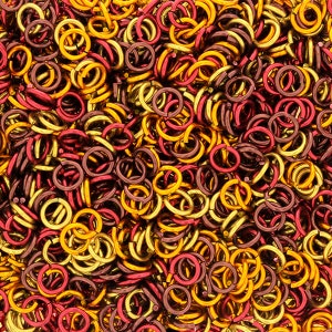 Puede incluir: Un mont&oacute;n grande de peque&ntilde;os anillos de salto met&aacute;licos en colores dorado y burdeos. Los anillos est&aacute;n entrelazados y crean un patr&oacute;n texturizado, similar a una cadena.