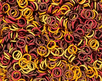 May include: A large pile of small, metallic jump rings in gold and burgundy colors. The rings are interlocked and create a textured, chain-like pattern.