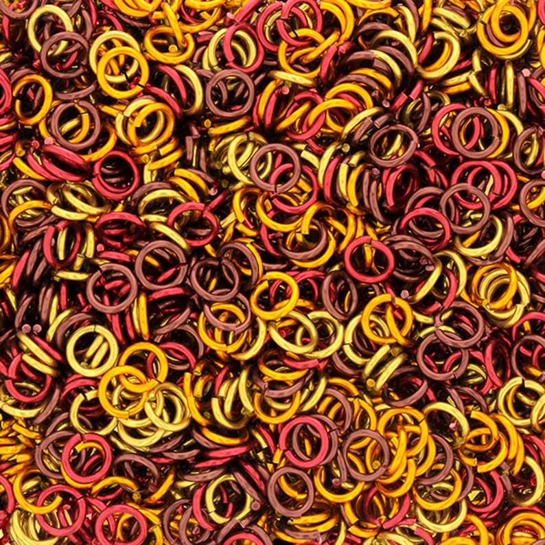 Puede incluir: Un mont&oacute;n grande de peque&ntilde;os anillos de salto met&aacute;licos en colores dorado y burdeos. Los anillos est&aacute;n entrelazados y crean un patr&oacute;n texturizado, similar a una cadena.