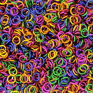 Puede incluir: Un mont&oacute;n grande de anillos de salto de metal de colores. Los anillos son de varios tonos de verde, azul, morado, rosa y dorado.