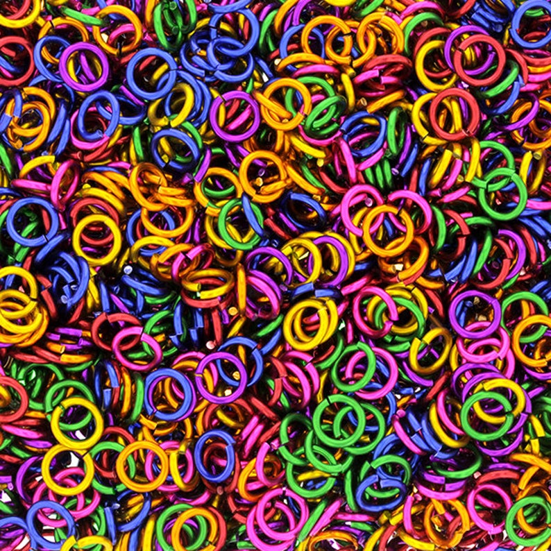 Puede incluir: Un mont&oacute;n grande de anillos de salto de metal de colores. Los anillos son de varios tonos de verde, azul, morado, rosa y dorado.
