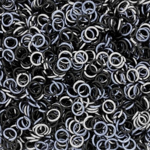 May include: A close-up image of a pile of silver and black metal jump rings. The jump rings are small and round, and they are all linked together.
