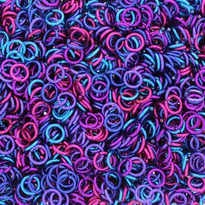 Puede incluir: Una imagen de primer plano de una gran cantidad de peque&ntilde;os anillos de salto met&aacute;licos. Los anillos son una mezcla de colores p&uacute;rpura y azul.