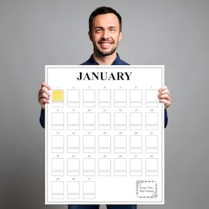 May include: A white wall planner for January, held by a person. The calendar has a grid of boxes for each day, with the word "JANUARY" at the top. The first box is highlighted in yellow. The bottom right corner has the text "Sticky Notes Wall Planner".