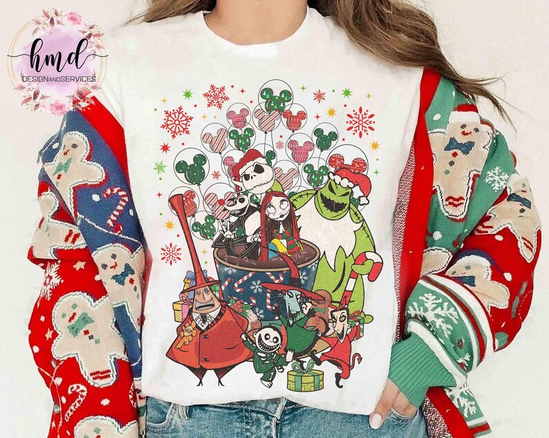 May include: A white t-shirt featuring a graphic print of characters from The Nightmare Before Christmas, including Jack Skellington, Sally, and Oogie Boogie, surrounded by festive holiday elements like snowflakes and Mickey Mouse balloons.
