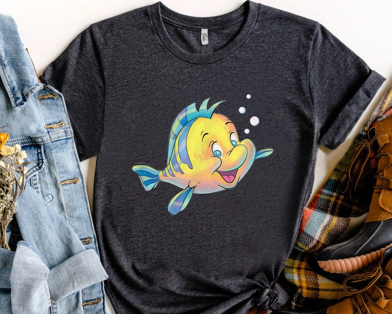 K&ouml;nnte beinhalten: Dunkelgraues T-Shirt mit einer Cartoon-Illustration eines gelb-blauen Fisches, der l&auml;chelt und Blasen hat. Der Fisch hat blaue Augen und schwimmt nach rechts. Das T-Shirt ist aus weichem Material.