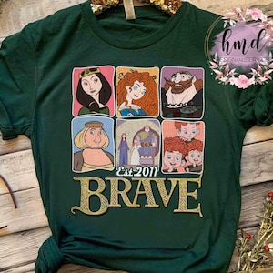 May include: A dark green t-shirt featuring a collage of cartoon character portraits from the movie "Brave." The word "BRAVE" is in gold lettering below the portraits, with "Est. 2011" above it. The shirt has a crew neck and short sleeves.