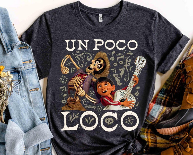 Peut inclure: T-shirt gris fonc&eacute; avec un graphisme color&eacute; du film Disney Coco. Le motif comprend un personnage squelette, un gar&ccedil;on jouant de la guitare et les mots "UN POCO LOCO" en blanc. Le t-shirt est &agrave; col rond.