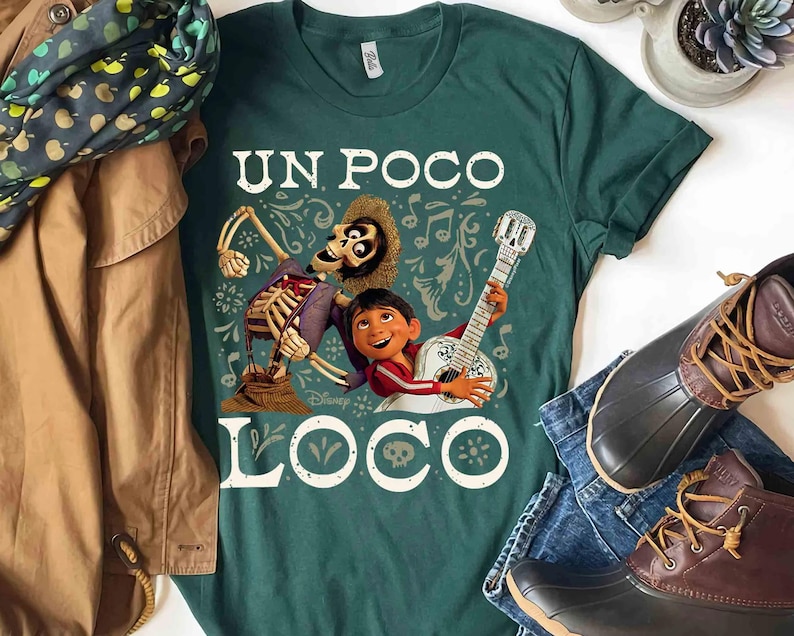 Peut inclure: T-shirt vert fonc&eacute; avec un motif du film Coco. Le design comprend un squelette, un gar&ccedil;on jouant de la guitare et les mots "UN POCO LOCO". Des notes de musique et des &eacute;l&eacute;ments d&eacute;coratifs entourent les personnages.