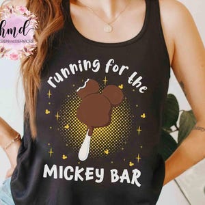 May include: Black tank top with the text "running for the MICKEY BAR" in white. The graphic features a Mickey Mouse ice cream bar in brown with a white stick, surrounded by yellow dots and stars.