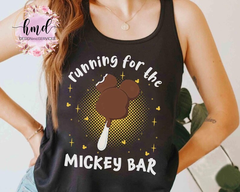 May include: Black tank top with the text "running for the MICKEY BAR" in white. The graphic features a Mickey Mouse ice cream bar in brown with a white stick, surrounded by yellow dots and stars.