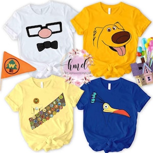 Puede incluir: Cuatro camisetas coloridas con diseños de personajes de dibujos animados. Una camiseta blanca presenta gafas, una nariz y una pajarita. Una camiseta amarilla tiene la cara de un perro. Otra camiseta amarilla tiene una banda de insignias. Una camiseta azul tiene un pájaro.