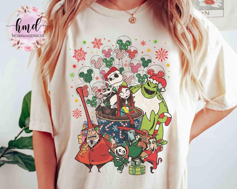 May include: A cream-colored t-shirt featuring a graphic print of characters from The Nightmare Before Christmas, including Jack Skellington, Sally, and Oogie Boogie, surrounded by festive holiday elements like snowflakes and Mickey-shaped balloons.