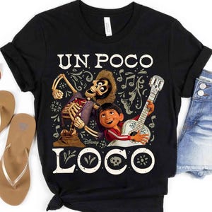Peut inclure: T-shirt noir avec un motif du film Disney Coco. Le design comprend le texte "UN POCO LOCO" avec des illustrations d'un personnage squelette, d'un gar&ccedil;on jouant de la guitare et d'&eacute;l&eacute;ments d&eacute;coratifs. Le t-shirt est associ&eacute; &agrave; un short en jean et des sandales.