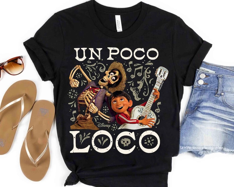 Peut inclure: T-shirt noir avec un motif du film Disney Coco. Le design comprend le texte "UN POCO LOCO" avec des illustrations d'un personnage squelette, d'un gar&ccedil;on jouant de la guitare et d'&eacute;l&eacute;ments d&eacute;coratifs. Le t-shirt est associ&eacute; &agrave; un short en jean et des sandales.