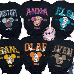 May include: Black t-shirts featuring characters from the movie Frozen. Each shirt has a character's name in a collegiate font, the year 2013, and the word "FROZEN". Characters include Kristoff, Anna, Elsa, Hans, Olaf, and Sven.