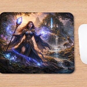 May include: Mousepad featuring a fantasy scene with a woman in a dark blue dress holding a staff with a glowing crystal. The background shows a waterfall, mountains, and a forest, with blue and purple magical effects.