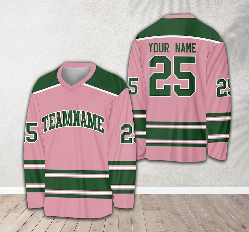 Pu&ograve; includere: Maglia da hockey rosa e verde con strisce bianche. La maglia ha il numero 25 sul davanti e il testo "YOUR NAME" sopra. Il retro della maglia ha il testo "TEAMNAME" e il numero 25 sulle maniche.