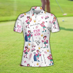 Puede incluir: Polo blanco con un estampado repetido de flamencos golfistas rosas, palos de golf, jarras de cerveza y texto. La camisa tiene cuello y mangas cortas. El texto incluye "Plan For The Day", "Par Then Bar", "Drink Repeat" y "Golf Friends".