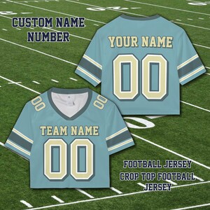 Puede incluir: Dos camisetas de f&uacute;tbol cortas de color verde azulado con detalles en blanco y dorado. Una camiseta muestra "TEAM NAME" y "00", la otra dice "YOUR NAME" y "00". Tambi&eacute;n se ve el texto "CUSTOM NAME NUMBER" y "FOOTBALL JERSEY CROP TOP FOOTBALL JERSEY".