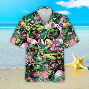 May include: A green, pink, and white short-sleeved button-up shirt with a tropical print featuring dinosaurs wearing bunny ears and holding Easter eggs.