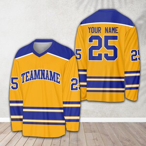 Pu&ograve; includere: Una maglia da hockey dorata con strisce blu e bianche. La maglia ha il testo "TEAMNAME" sul davanti e il numero "25" sul retro. Il testo "YOUR NAME" &egrave; sopra il numero.
