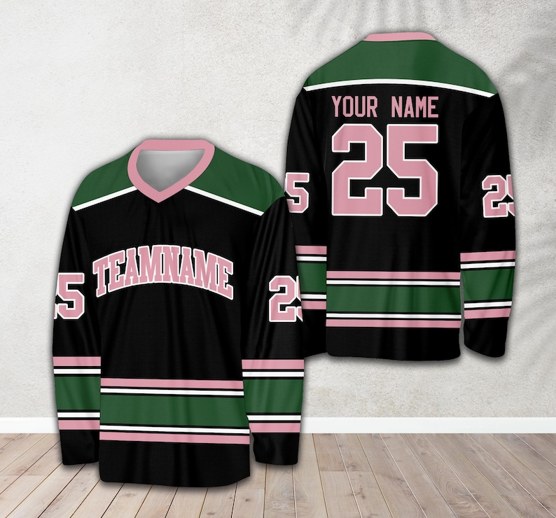 Pu&ograve; includere: Maglia da hockey nera con strisce verdi e rosa. La maglia ha il testo "TEAMNAME" in rosa e il numero "25" in rosa sul davanti. Il retro della maglia ha il testo "YOUR NAME" in rosa e il numero "25" in rosa.