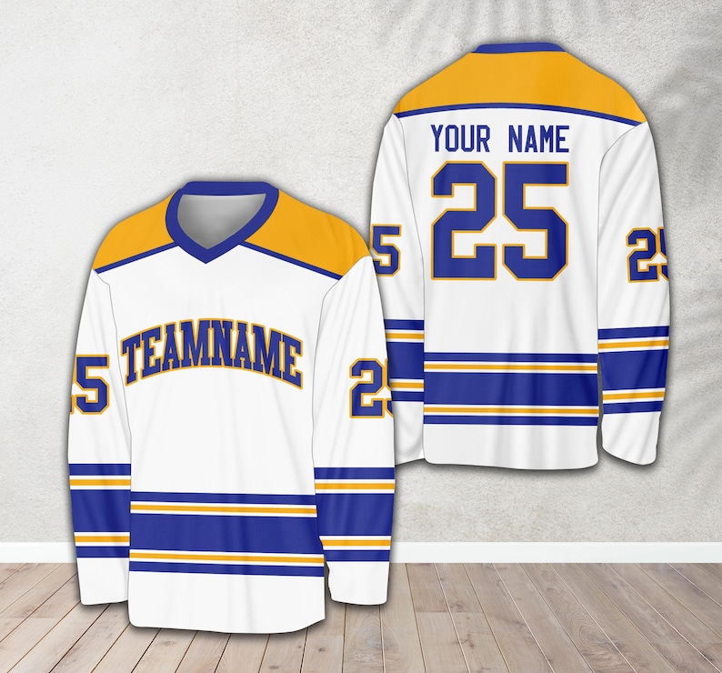 Pu&ograve; includere: Una maglia da hockey bianca con strisce blu e dorate. La maglia ha un collo a V e il numero 25 sul retro con il testo "YOUR NAME". La parte anteriore della maglia ha il testo "TEAMNAME" e il numero 25 sulle maniche.