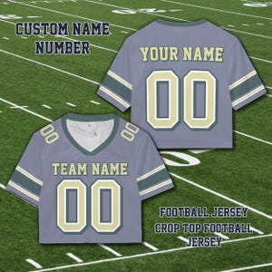 Puede incluir: Camiseta de f&uacute;tbol corta gris con el texto "TEAM NAME" y "YOUR NAME". La camiseta tiene el n&uacute;mero "00" en un color contrastante. Las mangas tienen rayas. Tambi&eacute;n se ve el texto "CUSTOM NAME NUMBER" y "FOOTBALL JERSEY CROP TOP FOOTBALL JERSEY".