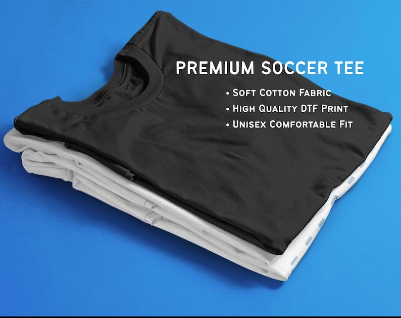 K&ouml;nnte beinhalten: Ein Stapel aus zwei T-Shirts, eines schwarz und eines wei&szlig;, vor blauem Hintergrund. Das schwarze Shirt oben zeigt "PREMIUM SOCCER TEE" und Details zu Stoff und Passform. Die Shirts sind sauber gefaltet.