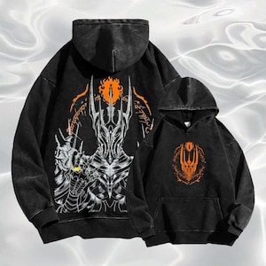 May include: Two black hooded sweatshirts with orange and white graphic designs. The larger sweatshirt features a detailed illustration of a character with a crown and text. The smaller sweatshirt has a simplified orange design.