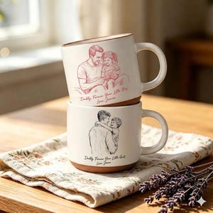 May include: Two white ceramic mugs stacked on a floral patterned cloth. The top mug features a red sketch of a father and child with the text "Daddy, Forever Your Little Boy, Love James." The bottom mug has a black sketch of a father and child with the text "Daddy, Forever Your Little Girl, Love James."
