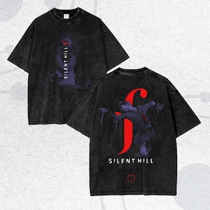 May include: Black, oversized t-shirts with a distressed wash. One shirt features the text "SILENT HILL" vertically with a purple graphic. The other shirt displays a large red "F" with a figure and the words "SILENT HILL".