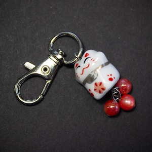 May include: A white ceramic mug with a black handle and the text "But First, Coffee" in a black, bold font. The mug is on a white surface. The mug is approximately 10 cm tall.