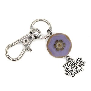 May include: A silver keyring with a purple and brown flower charm and a silver charm that says "World's Greatest Mom".