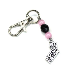 May include: A silver keyring with a pink and black beaded charm that says "Dog Person" with a paw print.