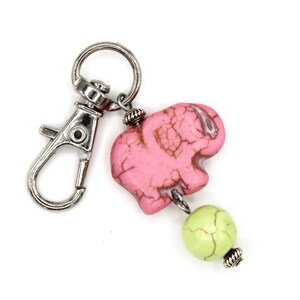 May include: A pink elephant charm with a green bead and a silver key chain.