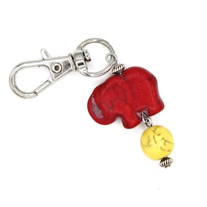 May include: A red elephant charm keyring with a yellow bead and a silver metal clasp.