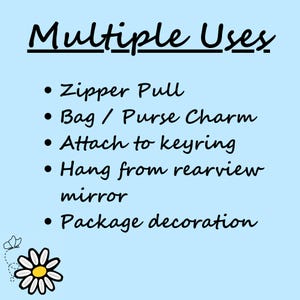 May include: Light blue background with black text listing multiple uses for a product. Text includes: zipper pull, bag/purse charm, attach to keyring, hang from rearview mirror, and package decoration. A daisy graphic is in the lower left corner.