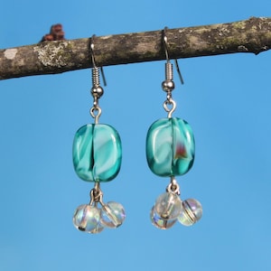 May include: Teal and white swirl glass earrings with iridescent clear glass beads hanging from the bottom.