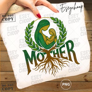 Peut inclure: Coussin blanc avec une illustration verte et dorée d'une mère et d'un enfant dans une couronne de laurier. Le mot "MOTHER" est écrit en vert avec des racines marron. L'image comprend le texte "Eseychoop" et "PNG".